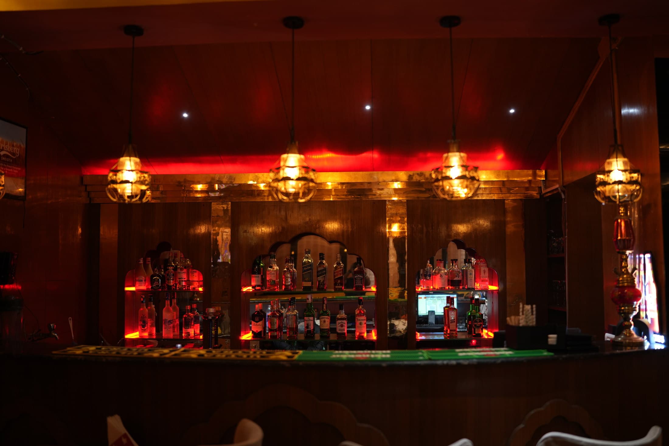 bistro Y bar counter with red-lit niches and brass lanterns